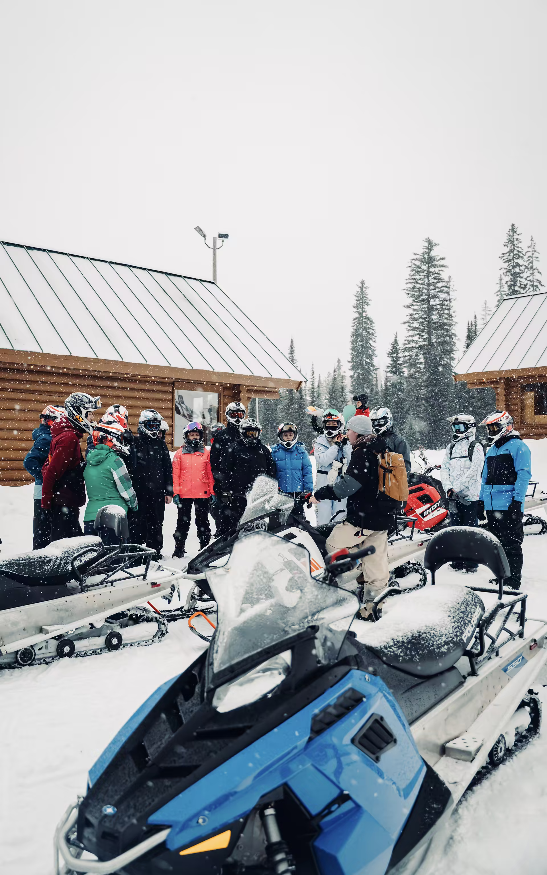 Riders and sleds gathered outside a lodge